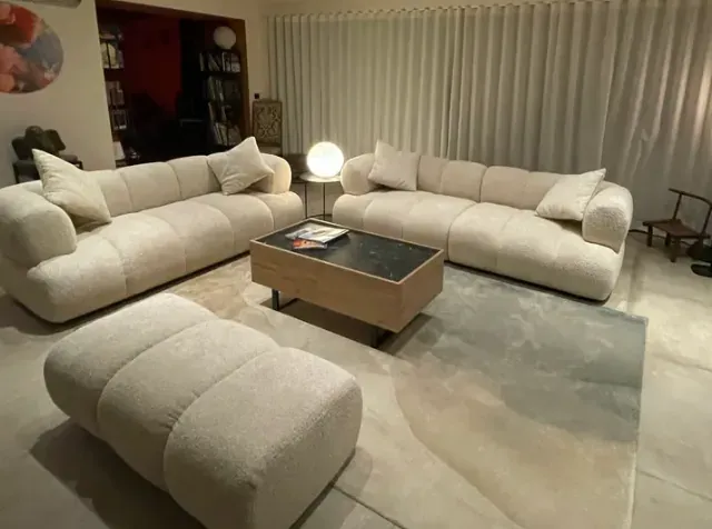 Salon avec deux canapés, un pouf et un tapis